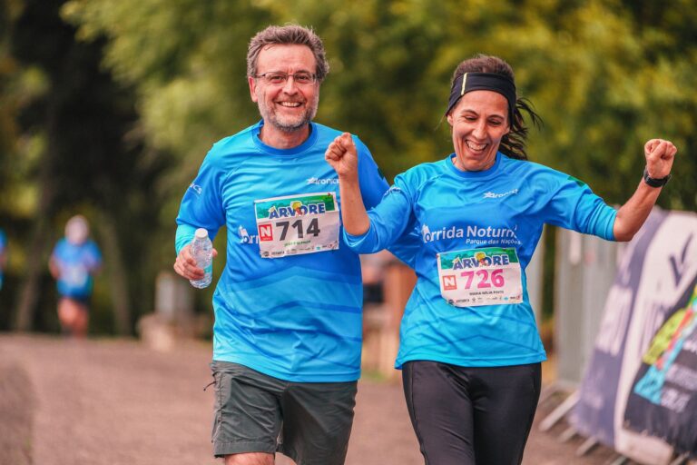 Two joyful runners crossing the finish line in a marathon race outdoors.