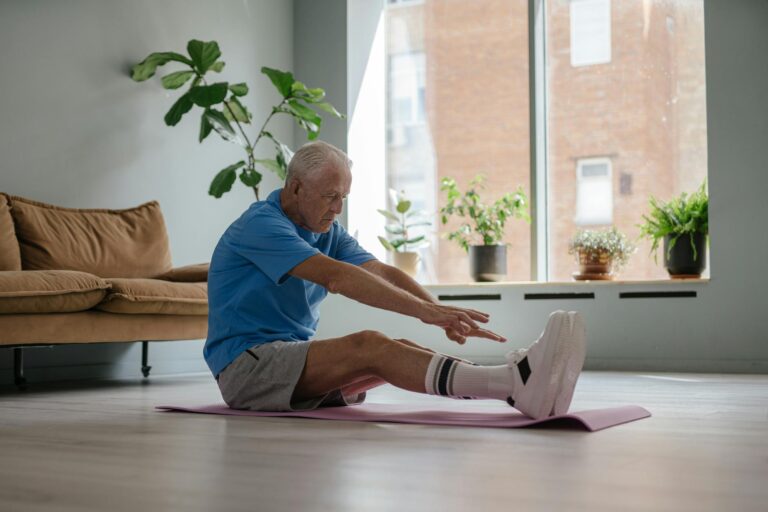 An elderly man exercises on a yoga mat indoors, showcasing healthy living.