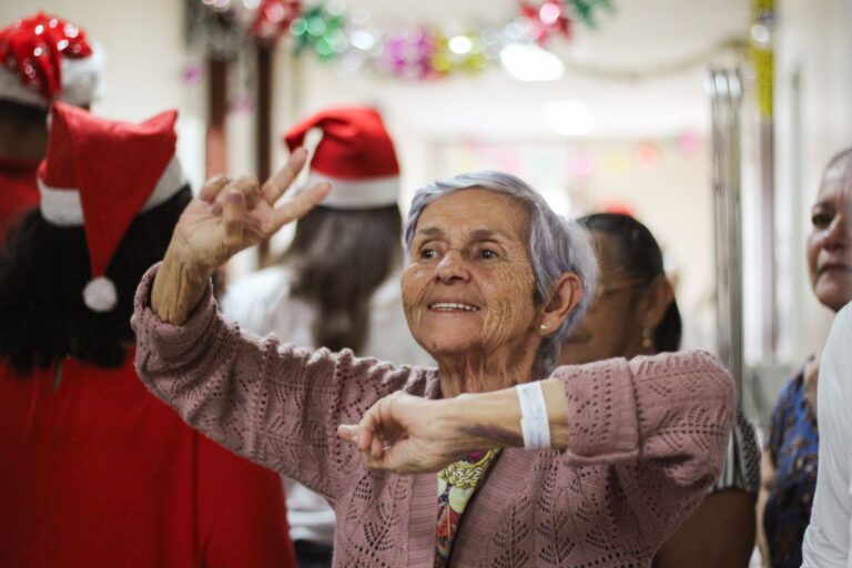 Joyful elderly woman celebrating indoors during a festive Christmas event.