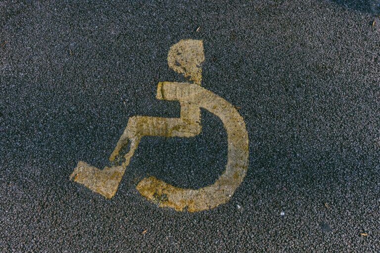 Close-up view of a weathered wheelchair symbol on asphalt, indicating disability access.