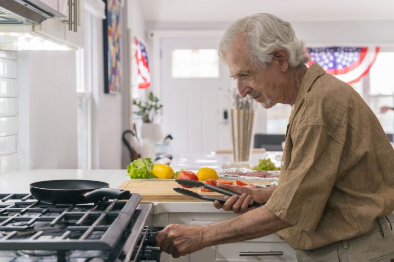 Elderly man enjoying home cooking preparation in a bright, modern kitchen.