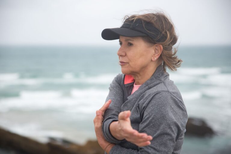 Elderly woman exercises by the sea, promoting a healthy lifestyle in Portugal.