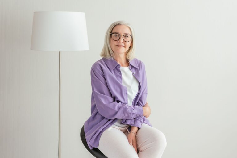 Portrait of a happy senior woman with glasses and white hair, wearing casual clothing.