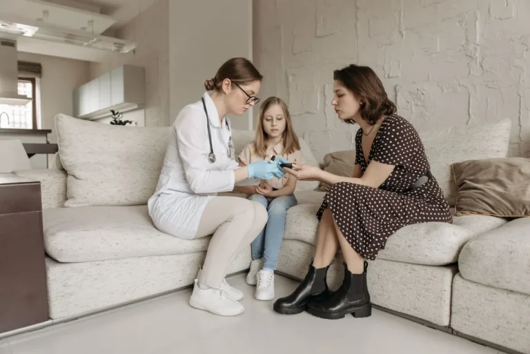 A medical professional examines a child's hand while the mother watches closely.
