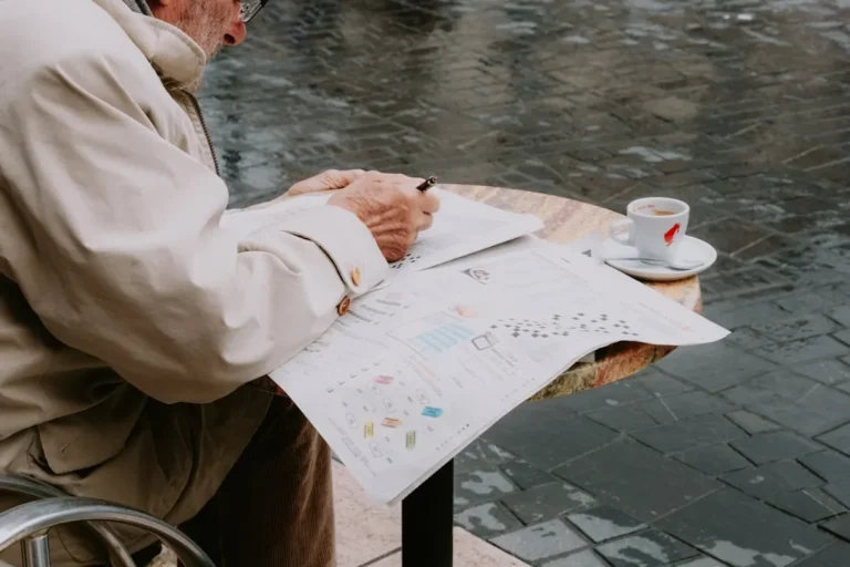 Um Homem Sentado Em Uma Mesa Escrevendo Em Um Pedaco De Papel Tno5Cc2Gyus