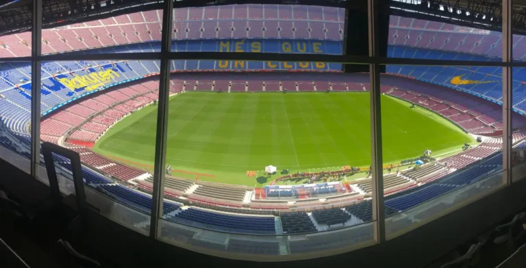 Wide view of Camp Nou stadium showcasing its vast seating and green pitch.