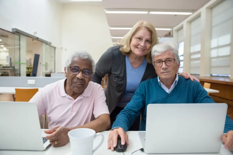 Elderly adults learning and enjoying computer class together indoors.