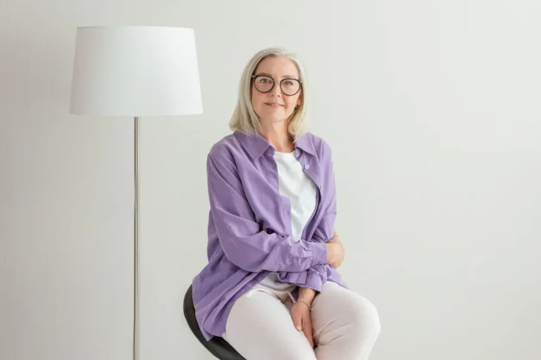 Portrait of a happy senior woman with glasses and white hair, wearing casual clothing.